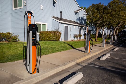 Sähköautojen latauspisteitä asuinrakennuksen parkkipaikalla.